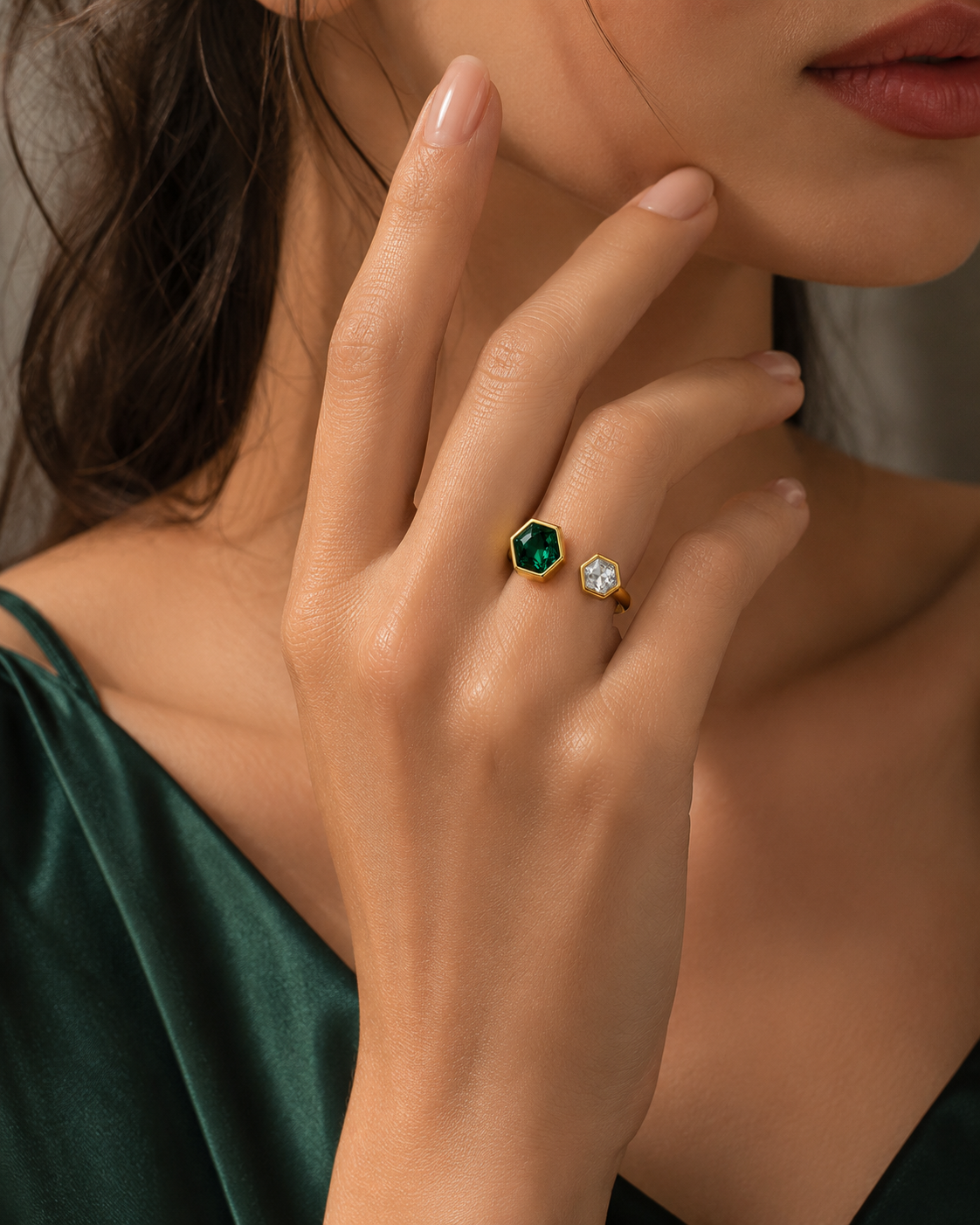 Open hexagon ring on hand: green and clear hexagon stones in gold settings