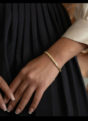Gold tennis bracelet with round clear crystals on a wrist, hinged clasp