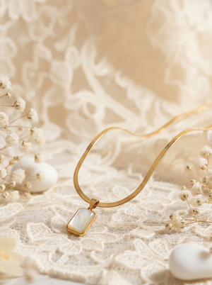 Gold necklace with a white pendant on a soft beige background