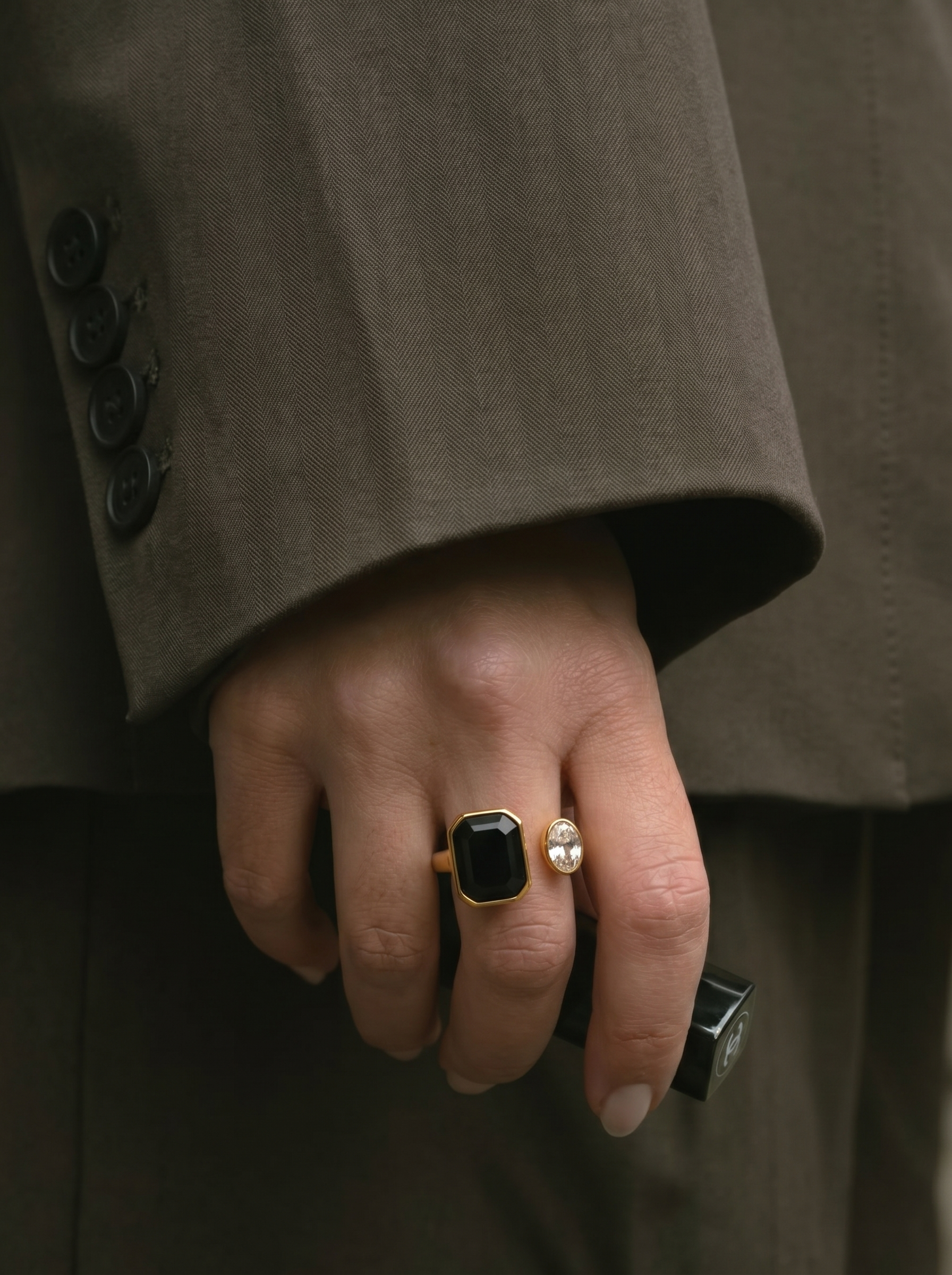 Close-up of a hand wearing two rings with a coat sleeve in the background