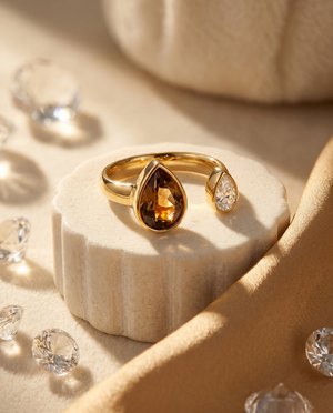 Gold open ring featuring large brown teardrop stone and small clear round stone