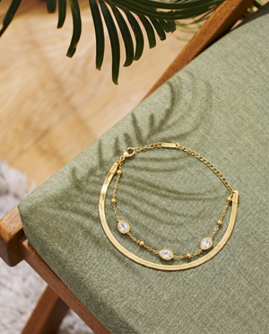 Gold layered chain bracelet with teardrop crystal charms and adjustable chain links.