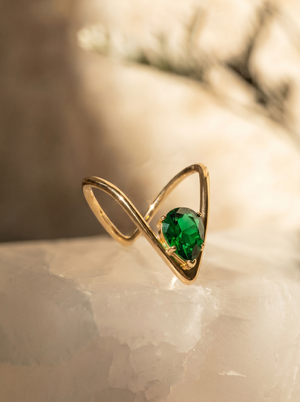 Gold-tone V-shaped solitaire ring with green oval gemstone, side view