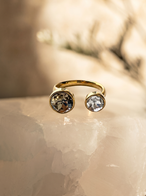 Gold ring with two gemstones on a soft beige background
