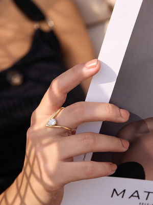 Gold open V ring on hand, featuring a round clear gemstone