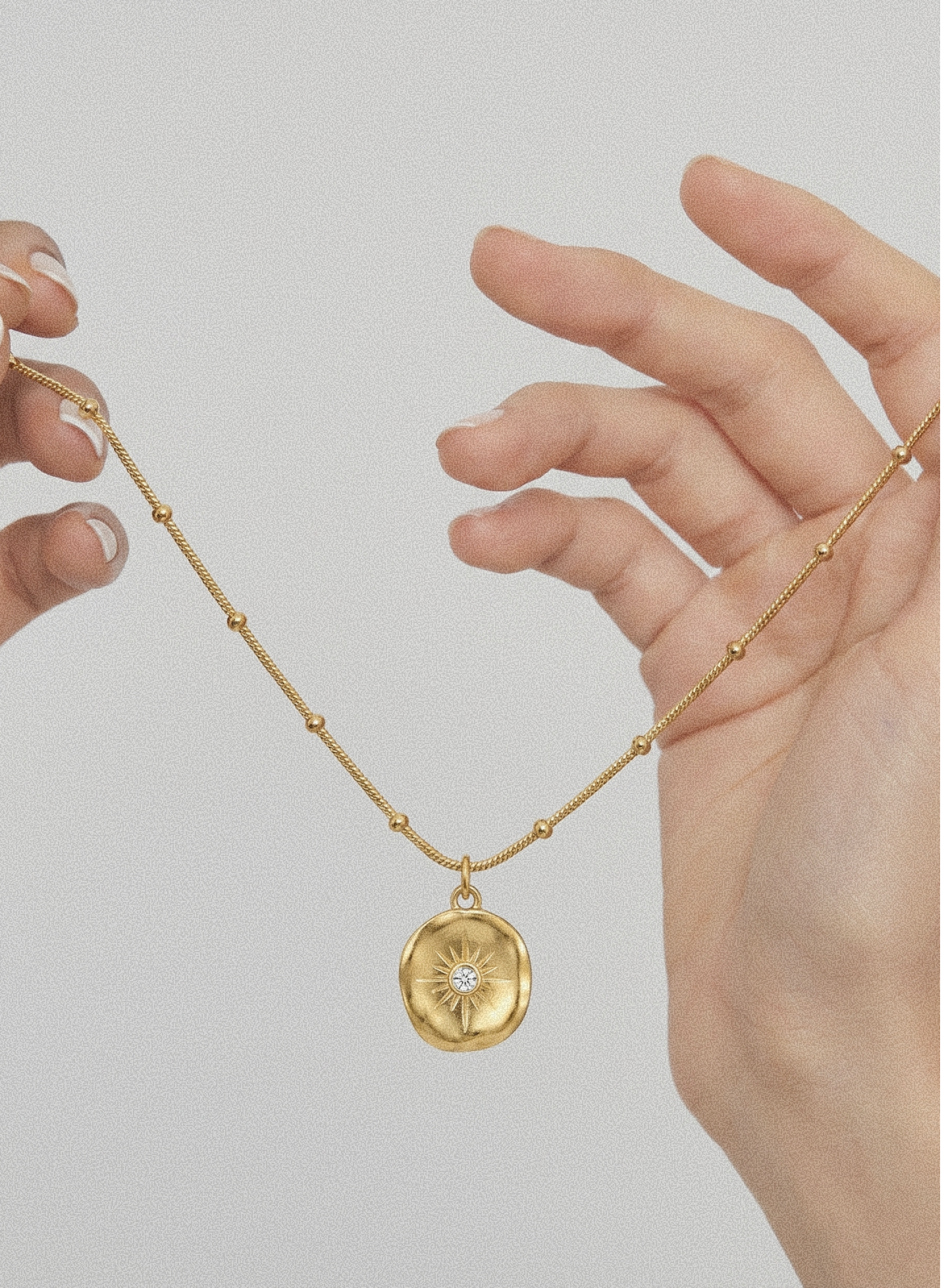 Gold-tone beaded chain pendant necklace with round sunburst medallion charm