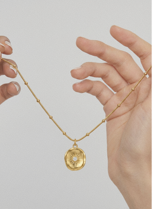 Gold-tone beaded chain pendant necklace with round sunburst medallion charm