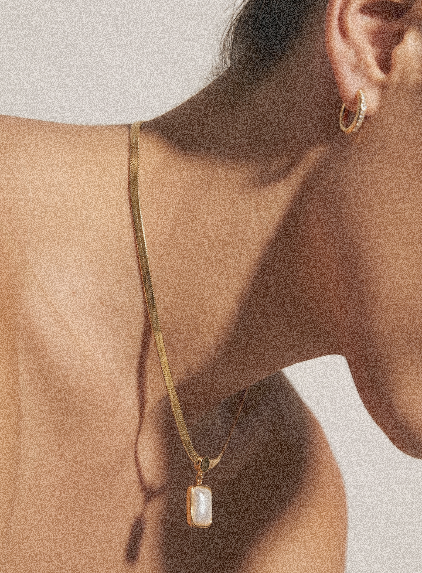 Gold-tone necklace with rectangular drop pendant against neckline