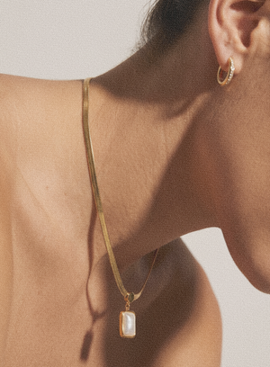 Gold-tone necklace with rectangular drop pendant against neckline