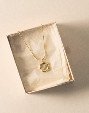 Gold-tone pendant necklace with round sunburst charm in gift box