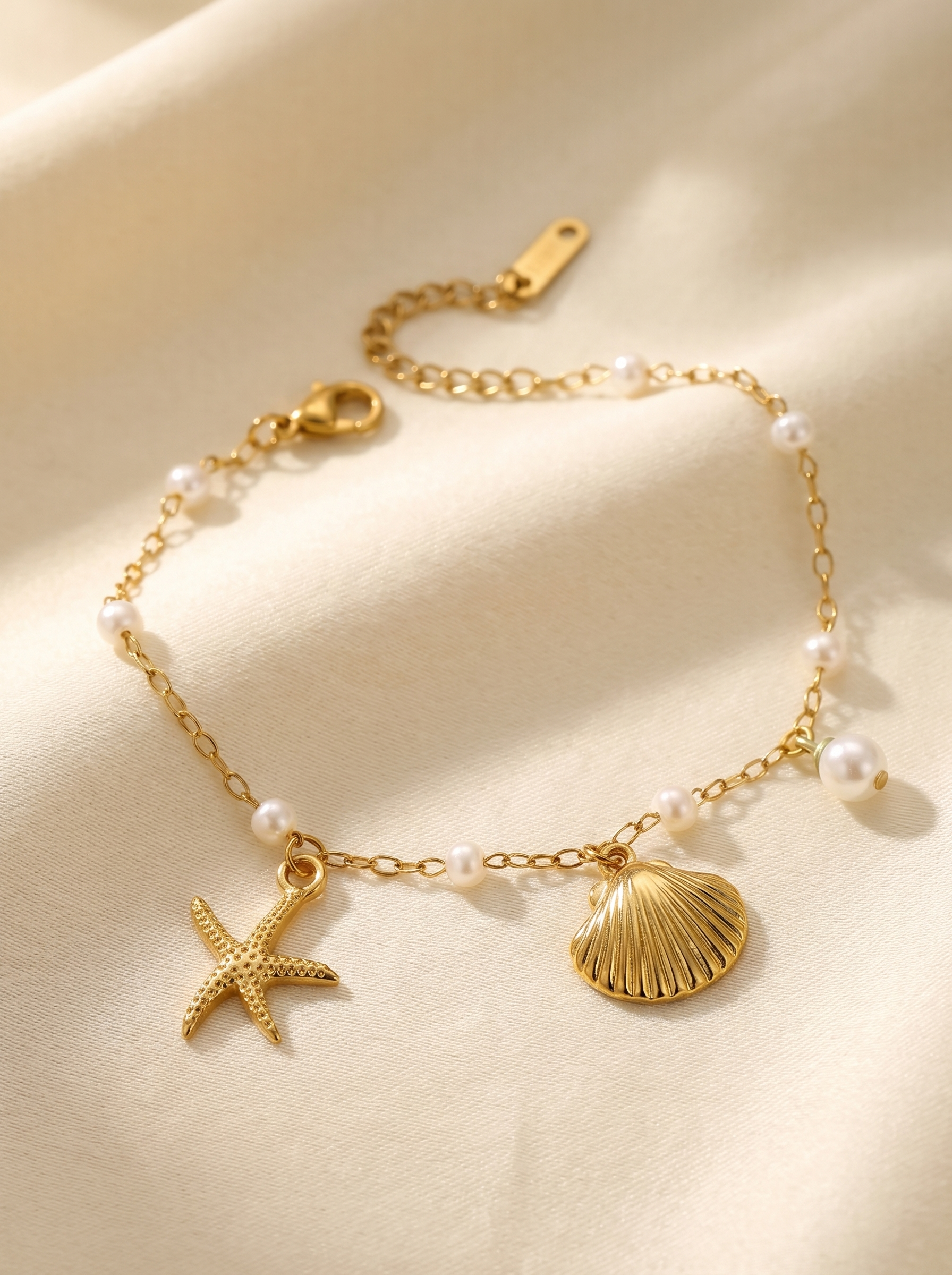 Gold pearl bracelet with starfish and shell charms on delicate linked chain