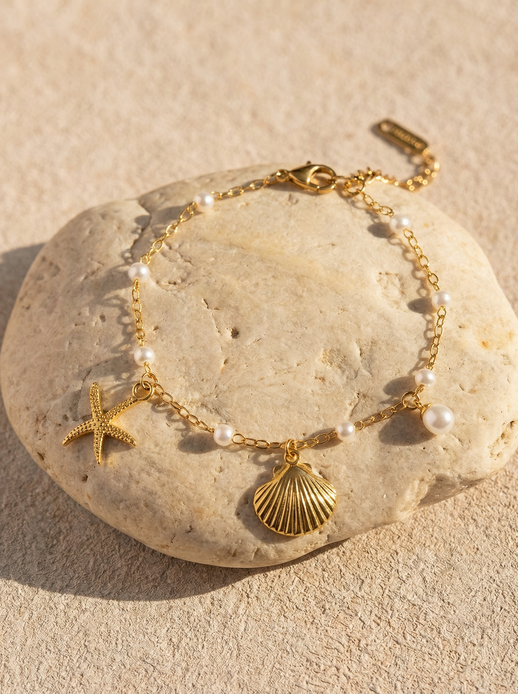 Gold pearl bracelet with starfish and seashell charms, adjustable chain clasp