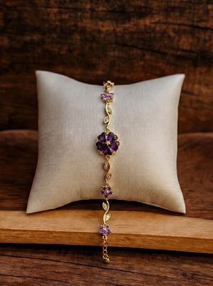 Gold bracelet with three purple floral charms and sparkling crystal links