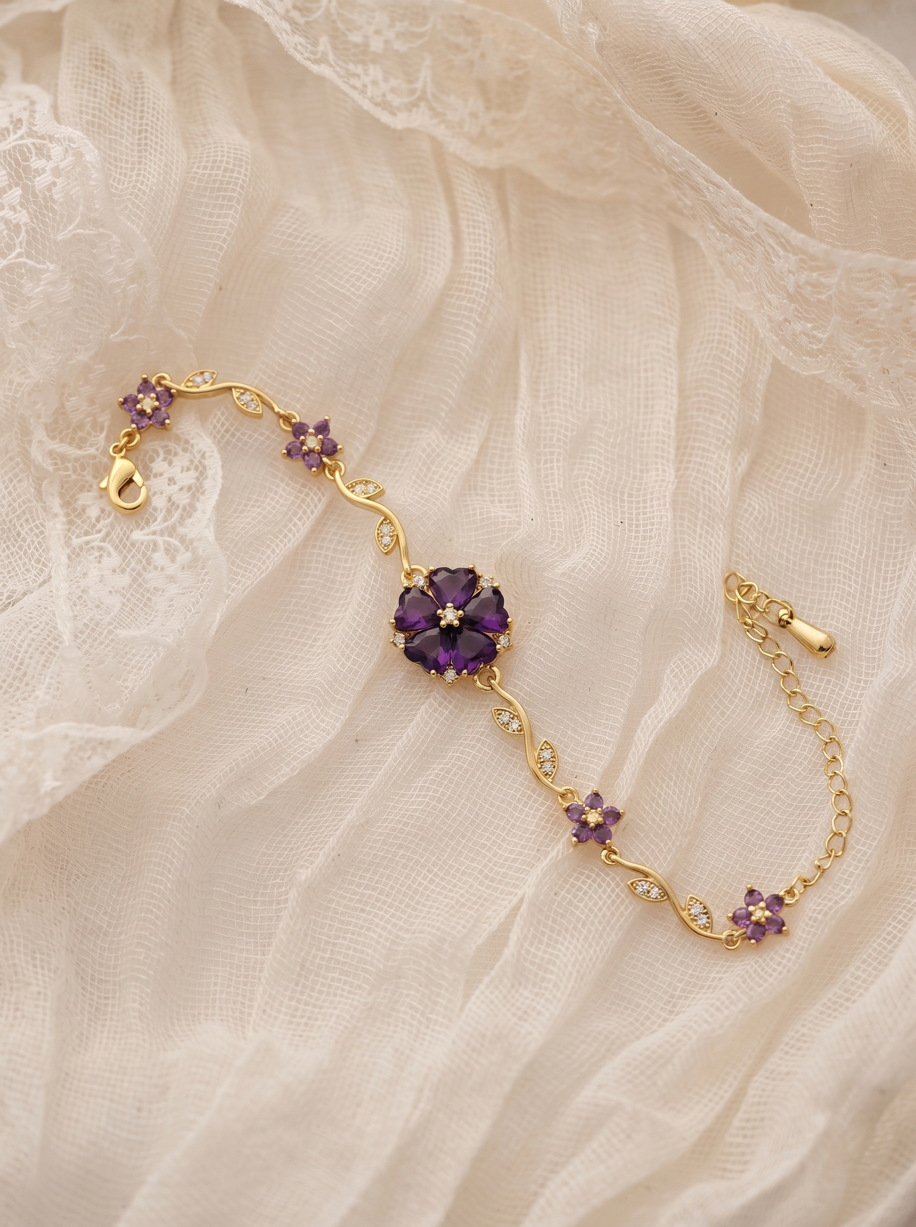 Gold bracelet with purple flower charms and curved crystal links, clasp visible