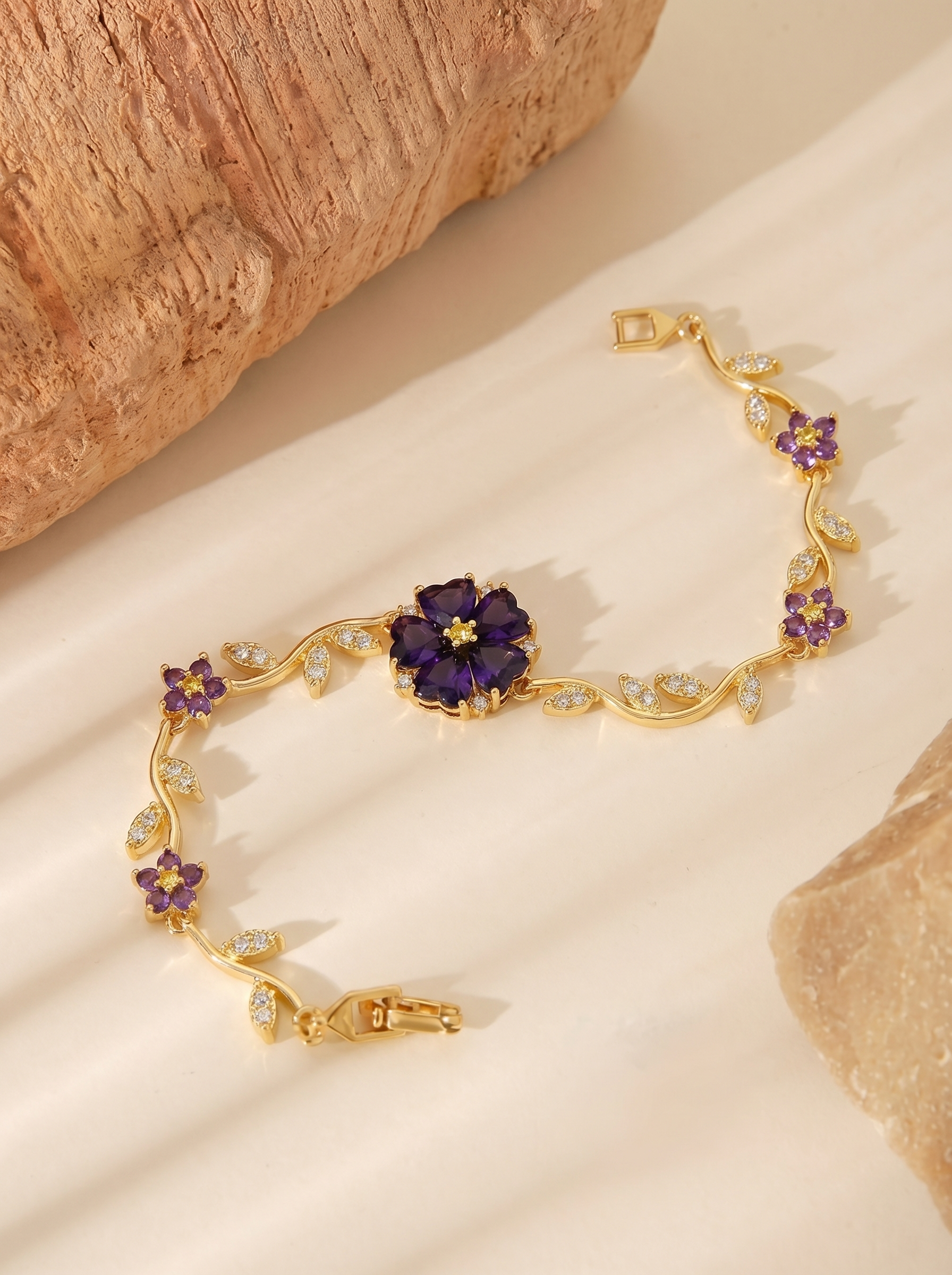 Gold bracelet with purple bloom centerpiece and dangling charm, crystal detail