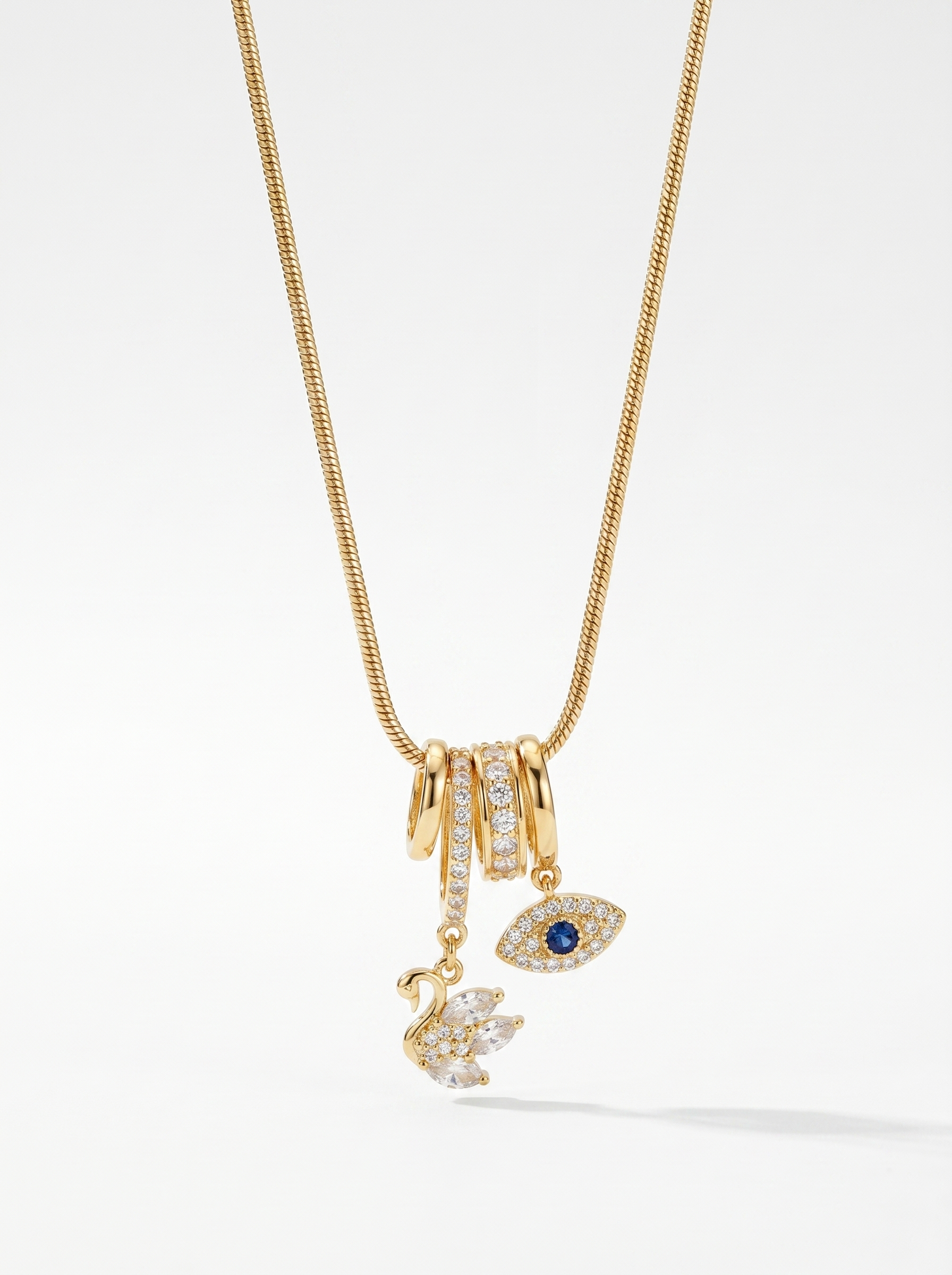 Gold charm pendant necklace with blue evil-eye enamel and small swan charms