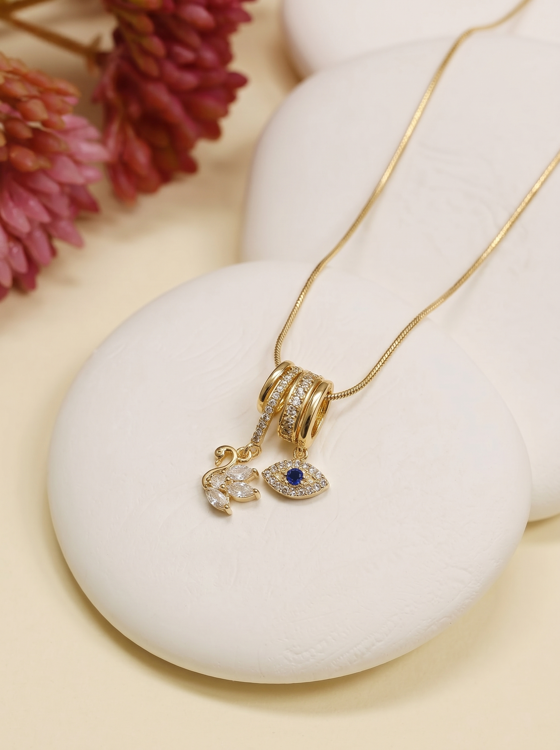 Gold charm pendant necklace with blue evil-eye charm and swan accent on hoop links