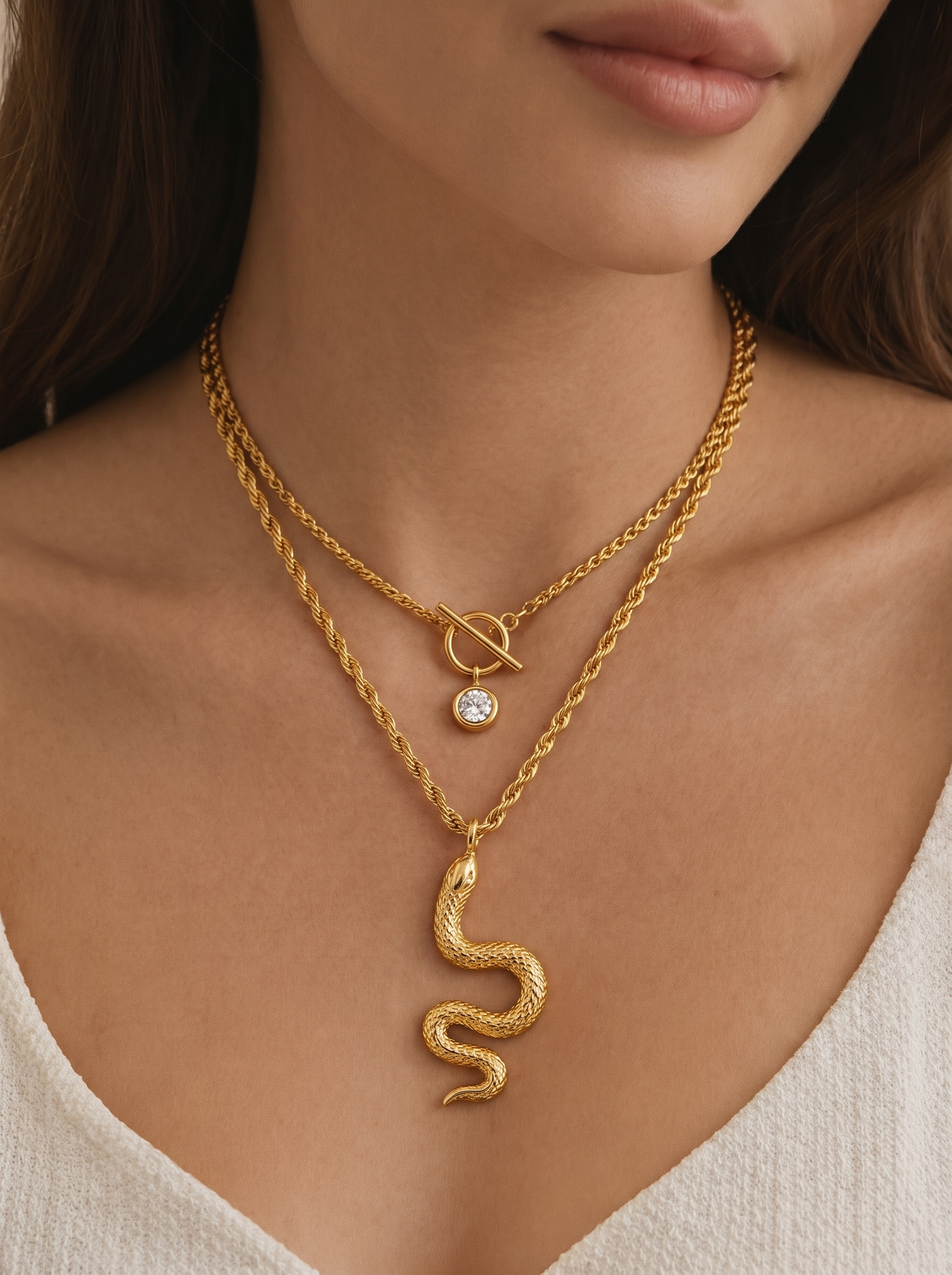 Gold-tone layered snake charm necklace on model with round crystal and knot pendant