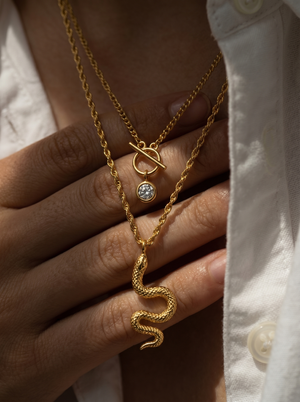 Gold-tone layered snake charm necklace close-up with round crystal charm and snake pendant