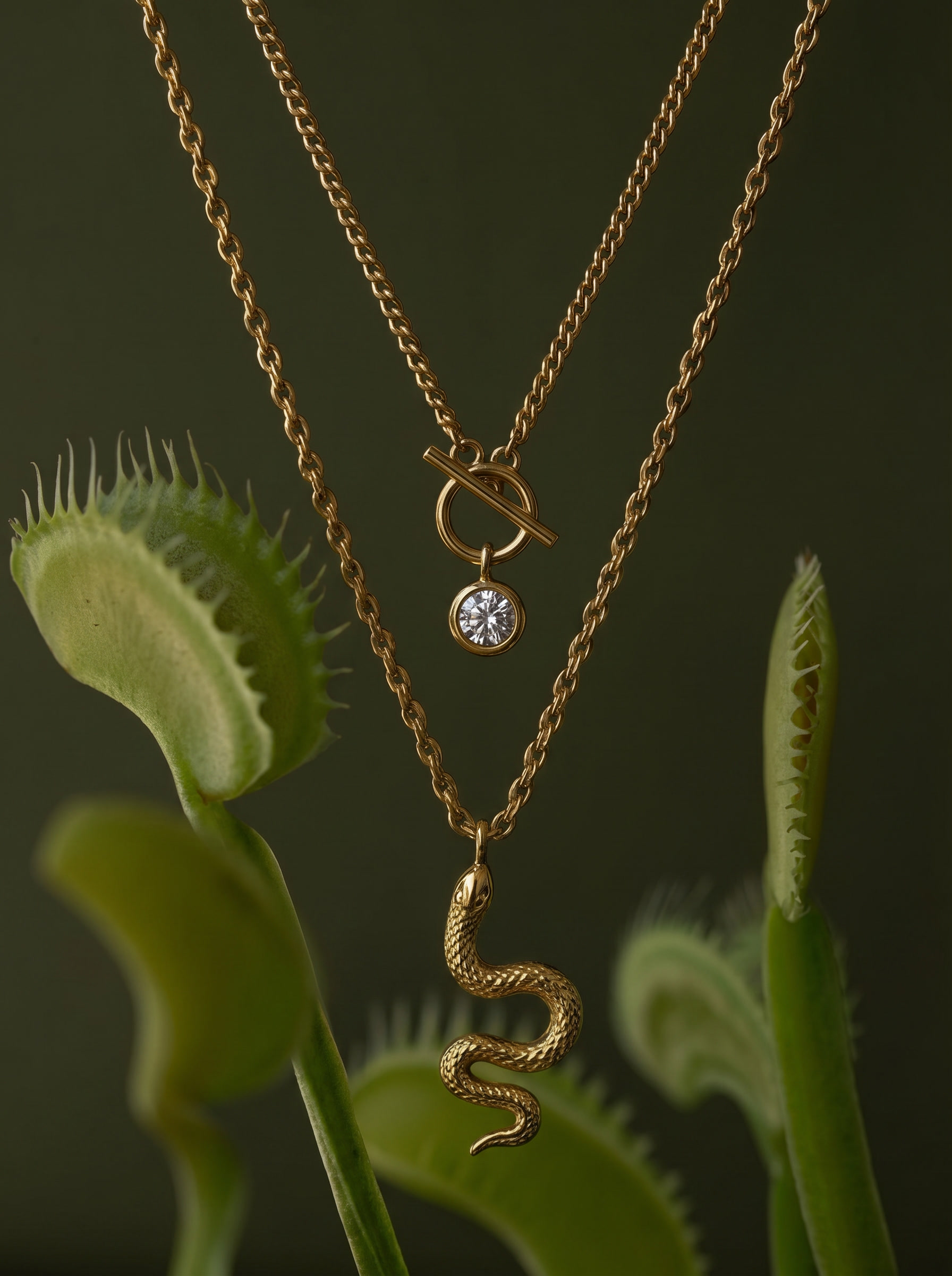 Gold-tone layered snake charm necklace with snake drop and round crystal knot charm