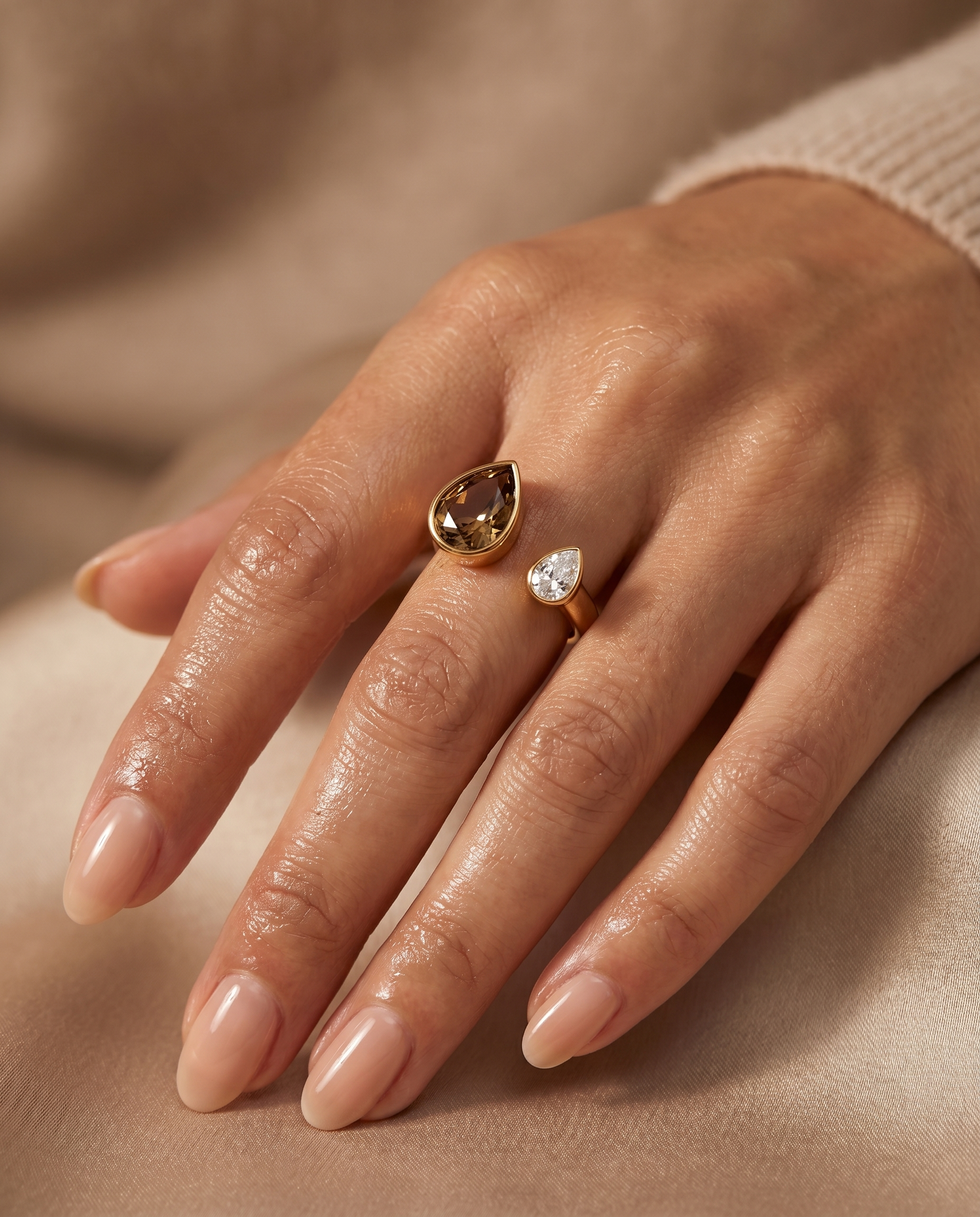 Gold open ring with brown teardrop and clear round stones, worn on finger