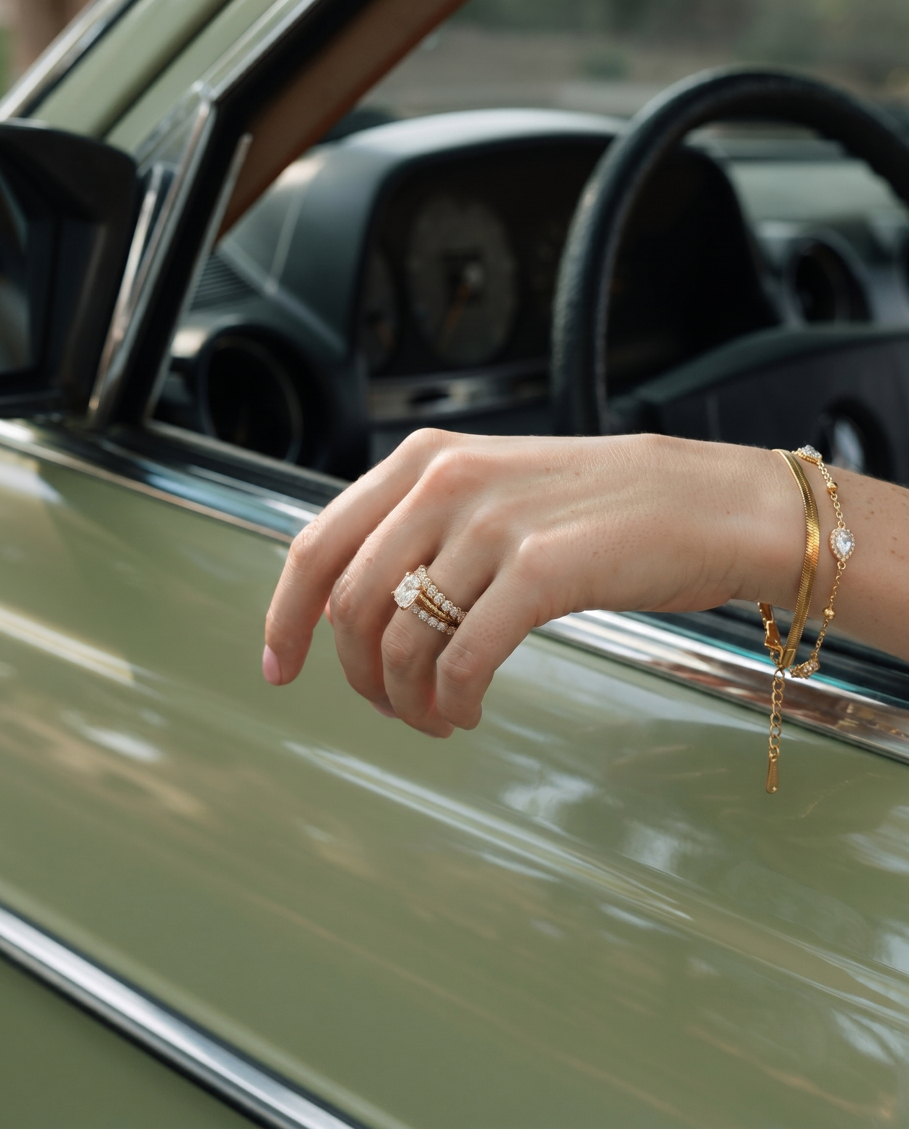 Gold layered chain bracelet with teardrop crystal charms worn on wrist.