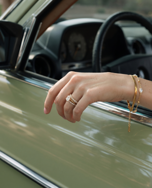 Gold layered chain bracelet with teardrop crystal charms worn on wrist.