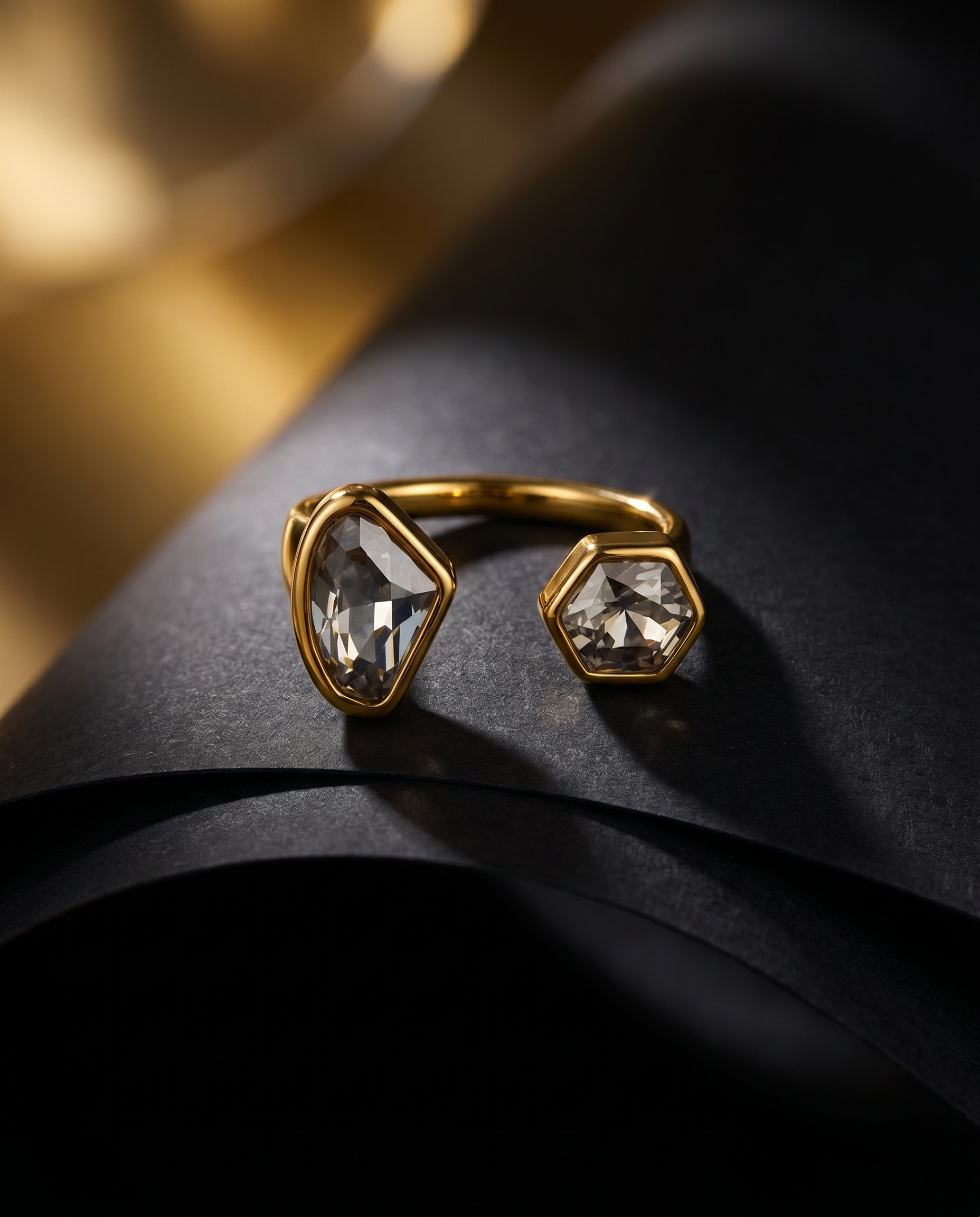 Gold ring with geometric gemstones on a dark surface