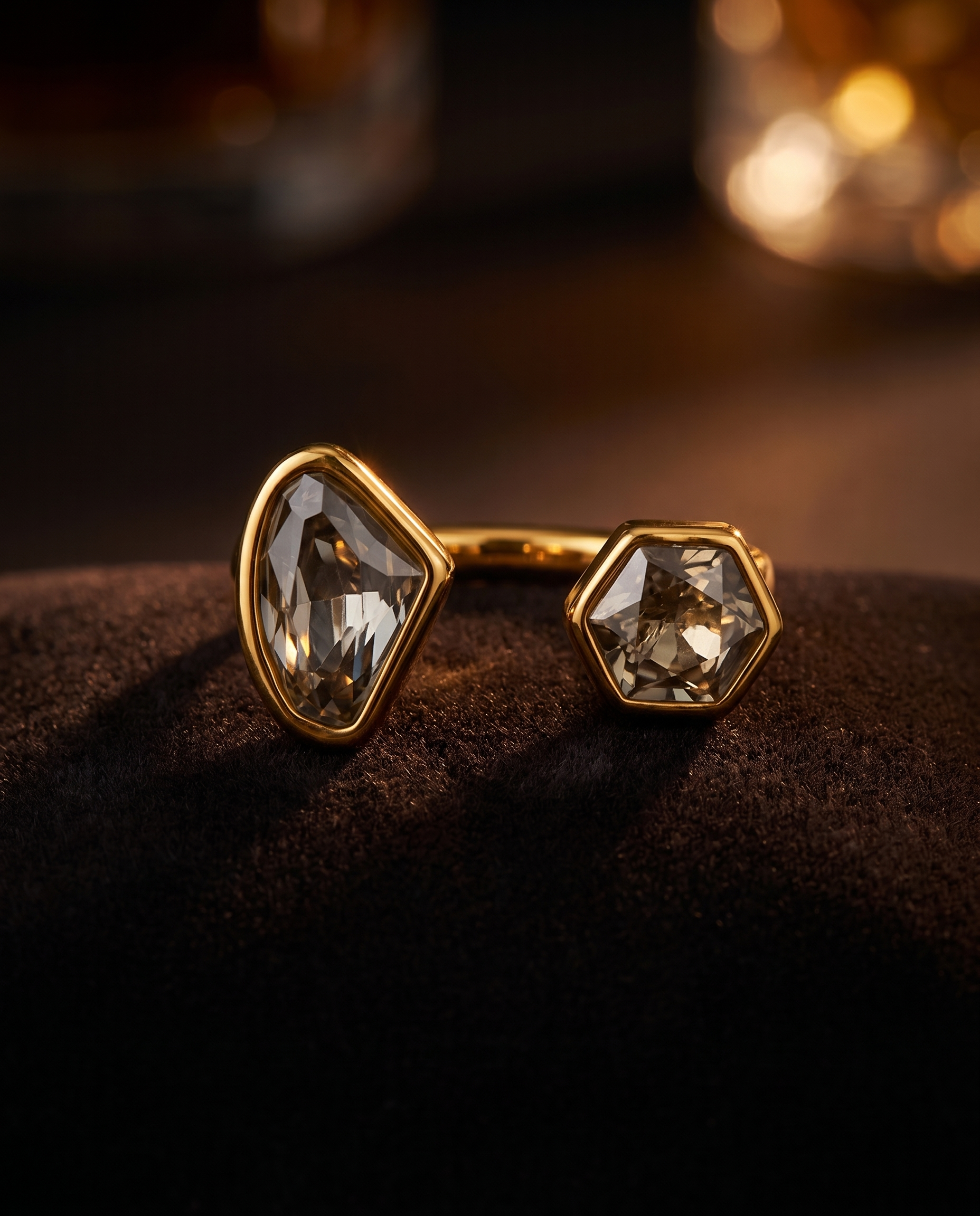 Gold earrings with clear gemstones on a dark surface
