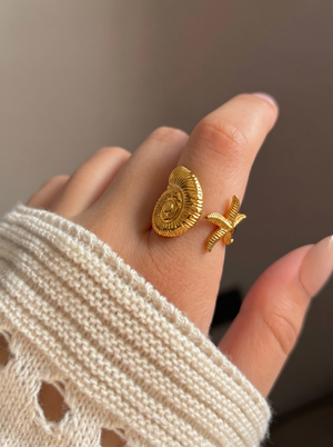 Gold-tone palm statement ring on hand, ridged disc with starfish detail