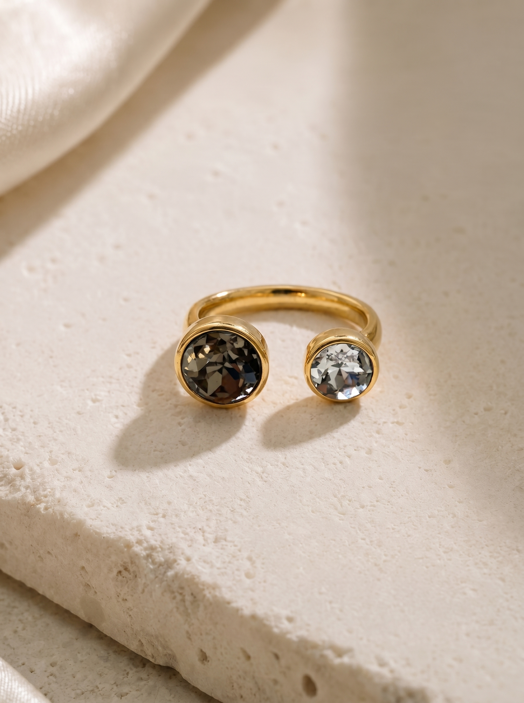 Gold ring with gemstones on a textured beige surface
