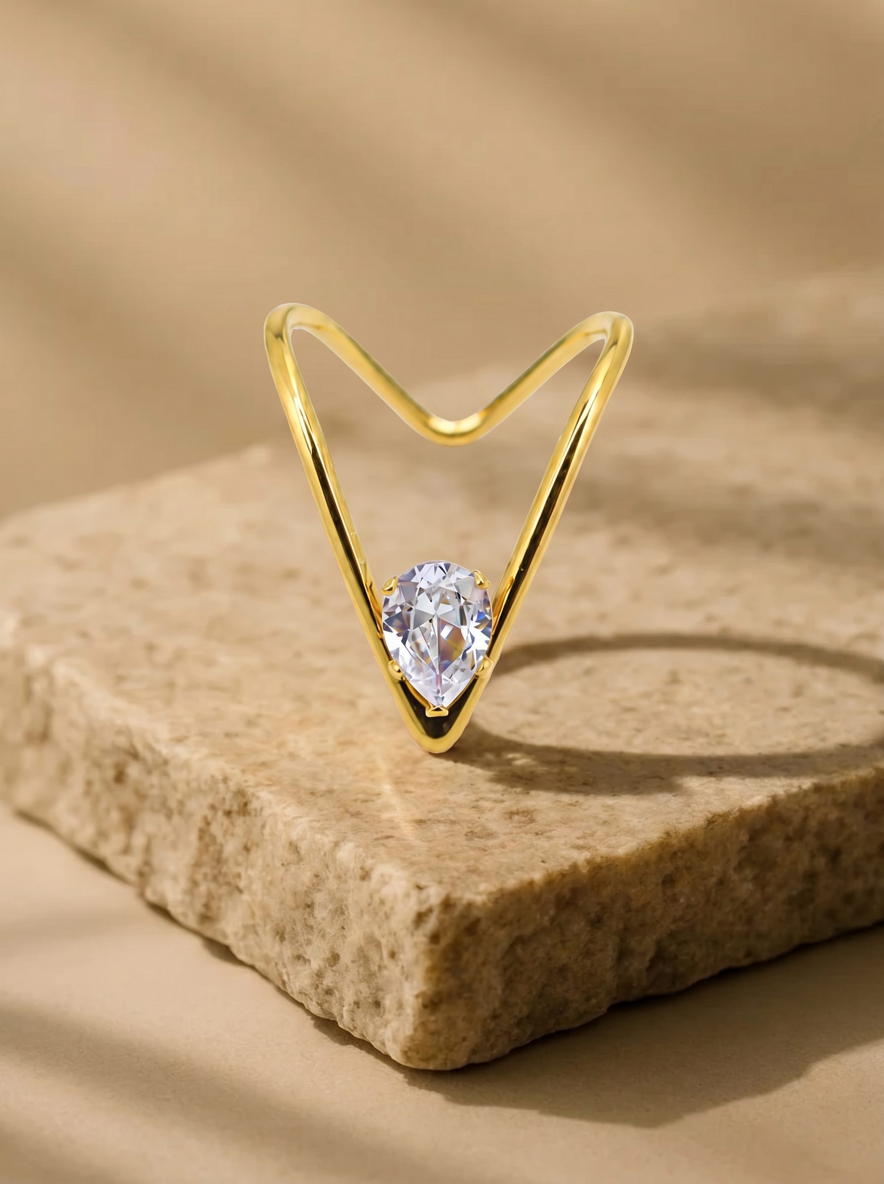 Gold open V ring with round clear gemstone on stone block